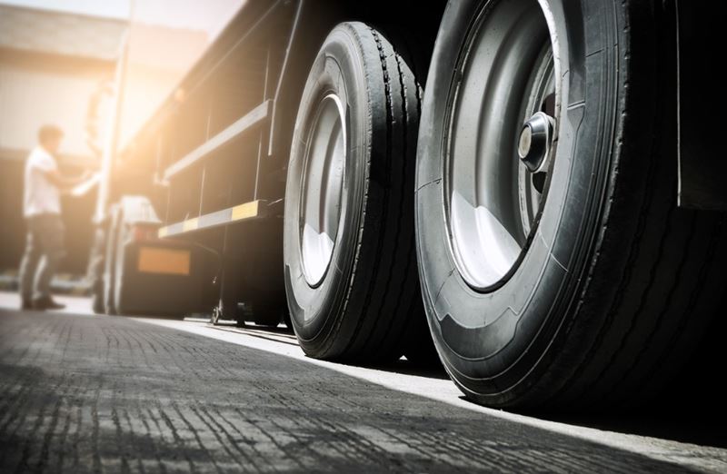 A truck driver is inspecting the outside of a semi truck.